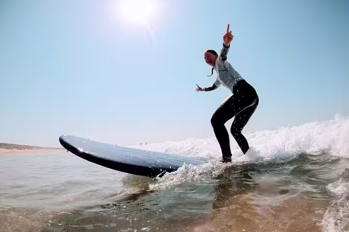 Surfer enjoying a sunny day riding waves in Lisbon, perfect for an exhilarating Surf & Wine tour experience.