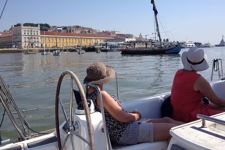 Passengers relax on a sailboat enjoying scenic views of Lisbon's historic waterfront on the Tagus River sailing tour.