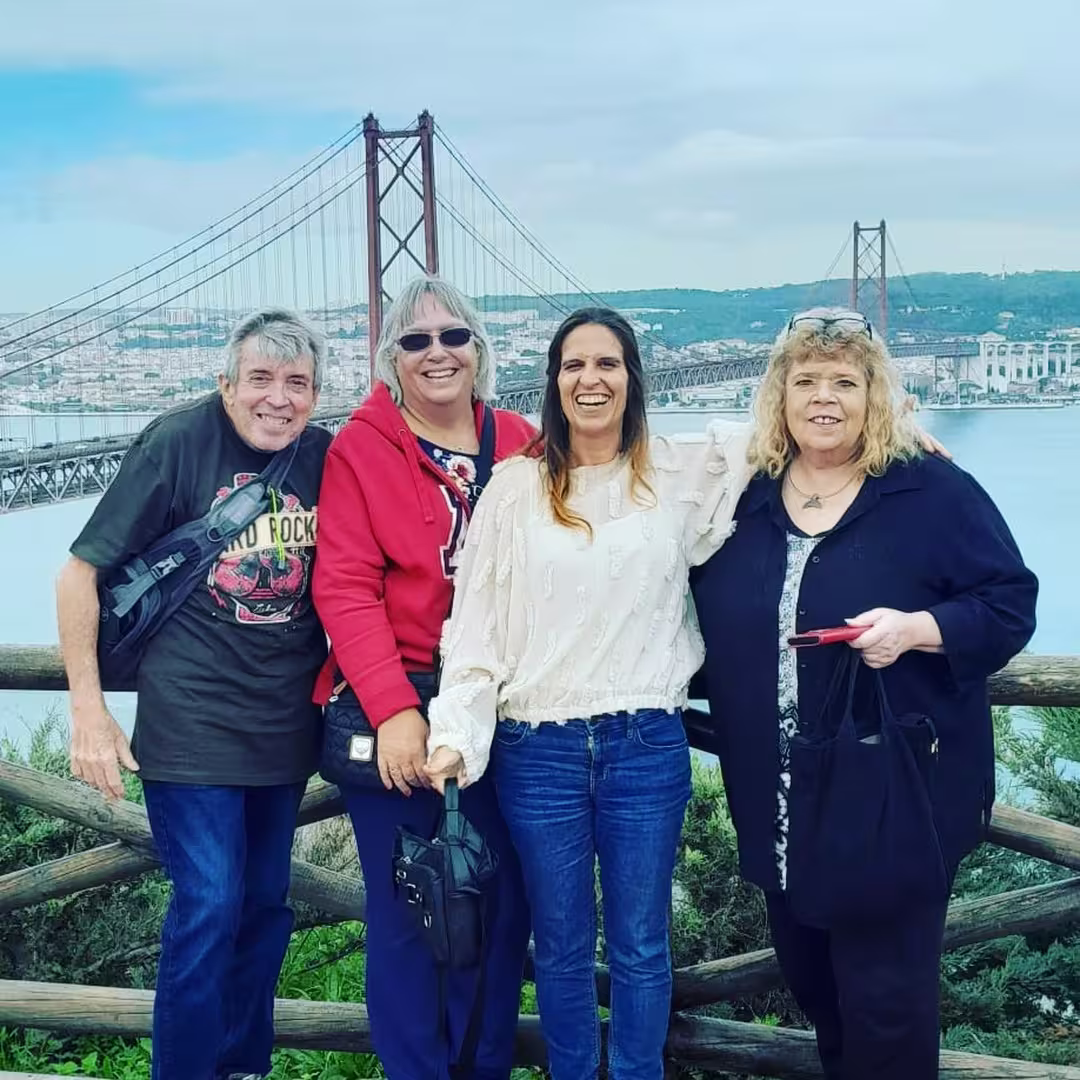 Group of travelers smiling with Lisbon's iconic bridge in the background, capturing the essence of the city tour.