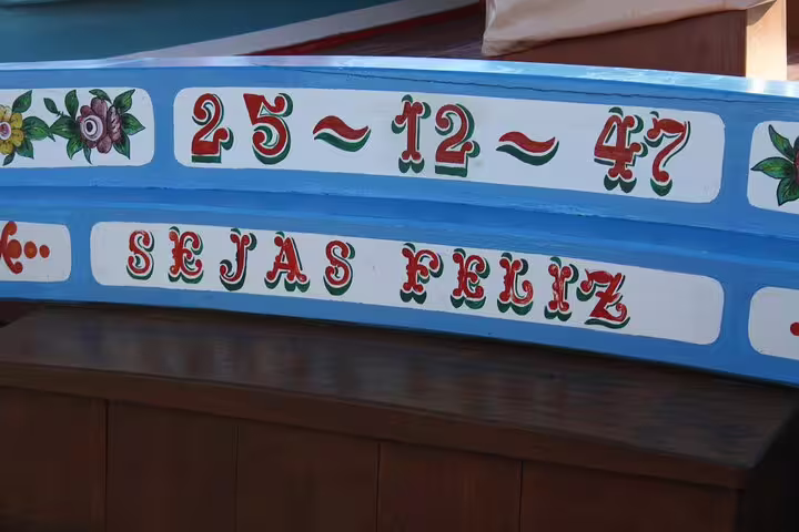 Close-up of vibrant traditional Lisbon boat with floral designs and 'Sejas Feliz' inscription, ideal for express cruises.