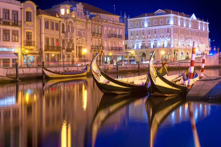 Scenic night view of gondolas on a canal in Aveiro, Portugal, illuminated by historic architecture, perfect for travel from Lisbon.