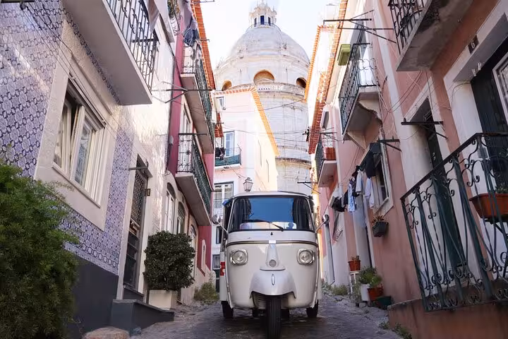 Tuk tuk on a narrow Alfama street in Lisbon Old Town, 1-hour sightseeing tour past azulejo facades