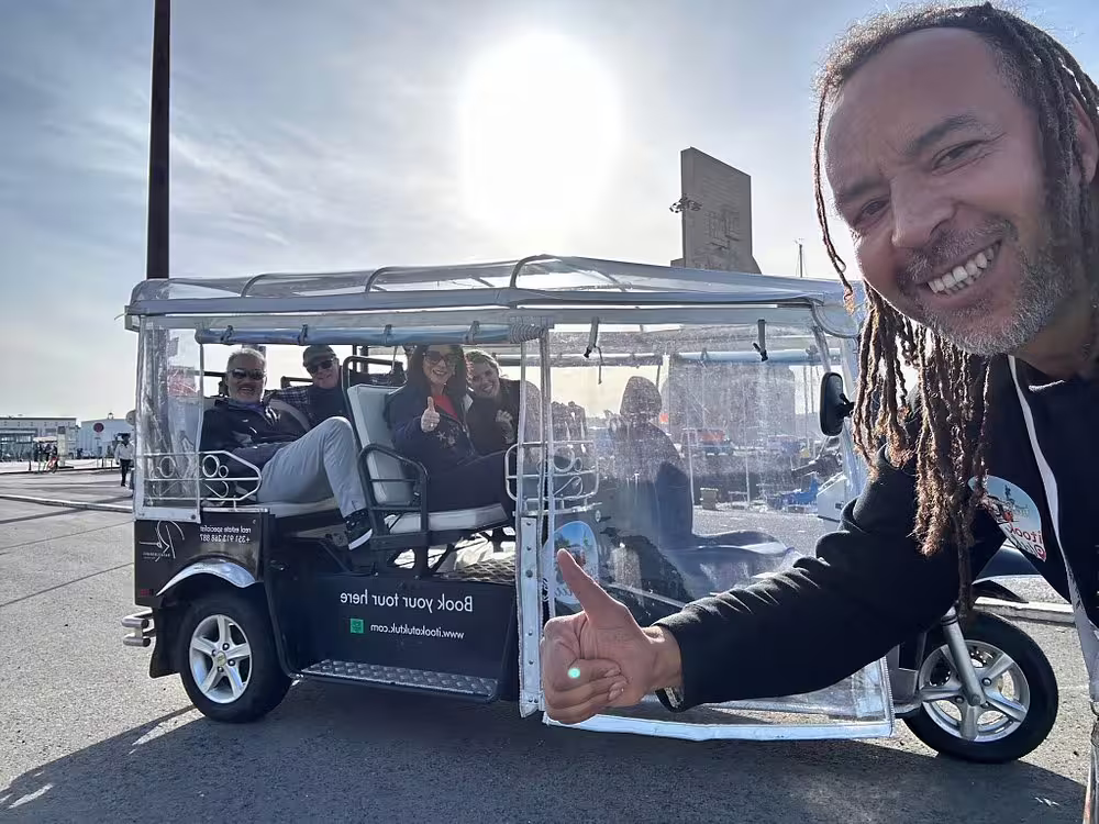 Smiling guide posing with tourists on a tuk tuk tour in Lisbon, highlighting the fun and engaging local experience.