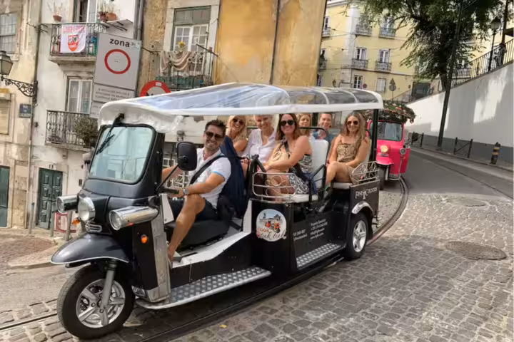 Tourists enjoying a scenic tuktuk ride through the historic streets of Lisbon's medieval and Belém districts.
