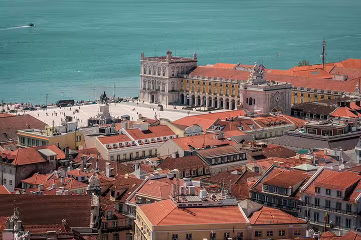 Aerial view of Lisbon's Praça do Comércio with vibrant red rooftops and the Tagus River, perfect for a TukTuk tour.