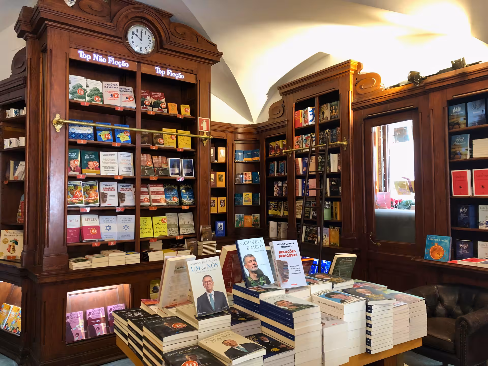 Vintage Lisbon bookstore interior with carved wooden shelves, a clock, and book displays on the old shops tour