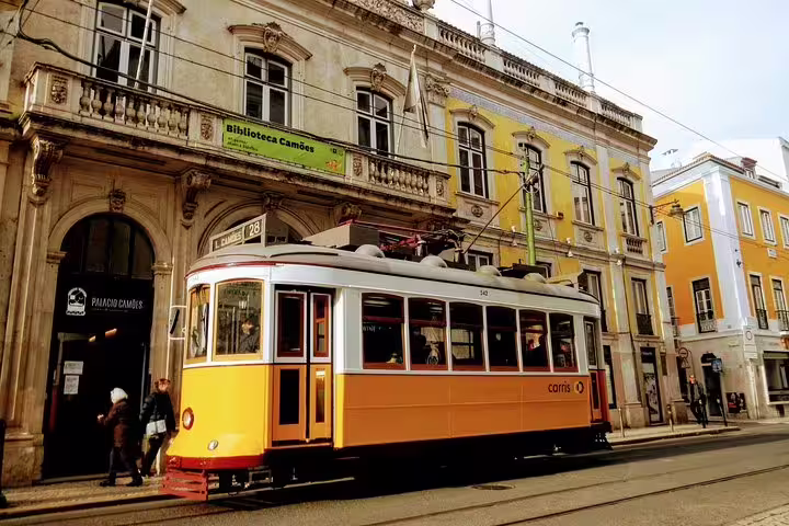 Vintage Lisbon tram passing historic Biblioteca Camões, capturing the charm of the World Heritage Deluxe Tour.