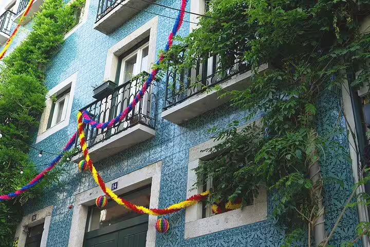 Colorful streamers adorn a traditional blue-tiled building, highlighting Lisbon's festive architecture.