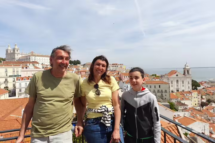 Family enjoying the scenic view of Lisbon's historic rooftops and the Tagus River during a walking tour.