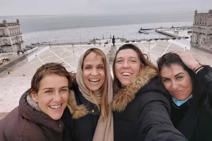 Happy tourists enjoy a scenic view of Lisbon's waterfront during a small group walking tour.