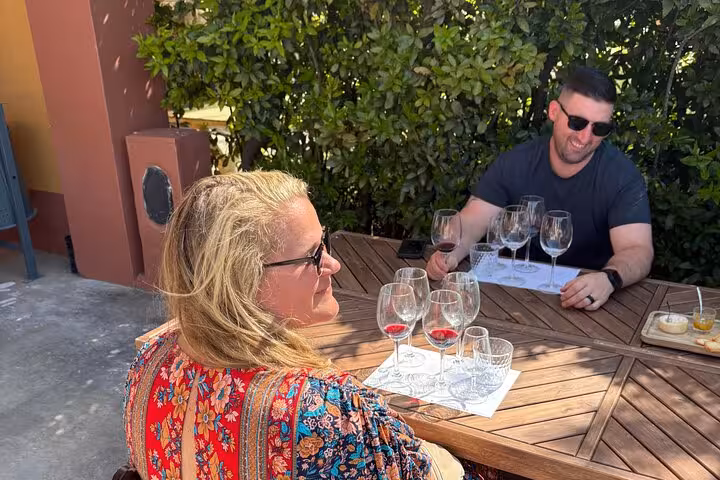 Couple sampling Portuguese wines at an outdoor winery table during Lisbon WineTour premium tastings with snacks