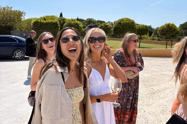Smiling guests holding wine glasses outside a Lisbon winery stop on an all-inclusive wine and food tasting tour