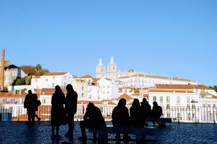 Silhouetted tourists enjoy panoramic views of Lisbon's historic architecture, highlighting the charm of the World Heritage Deluxe Tour.