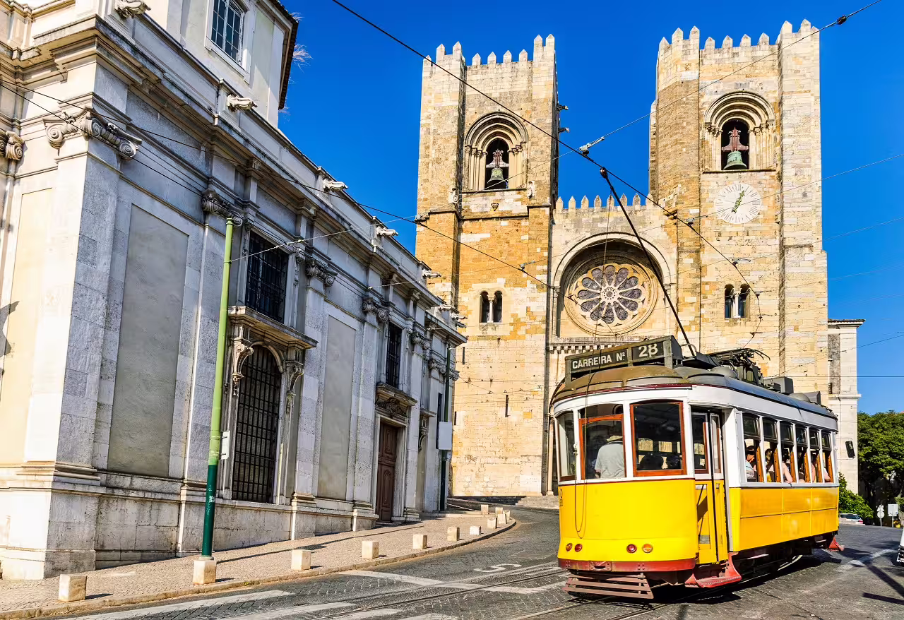 Historic yellow tram passing Lisbon Cathedral under blue skies, perfect for a 6-day cultural city break in Portugal.
