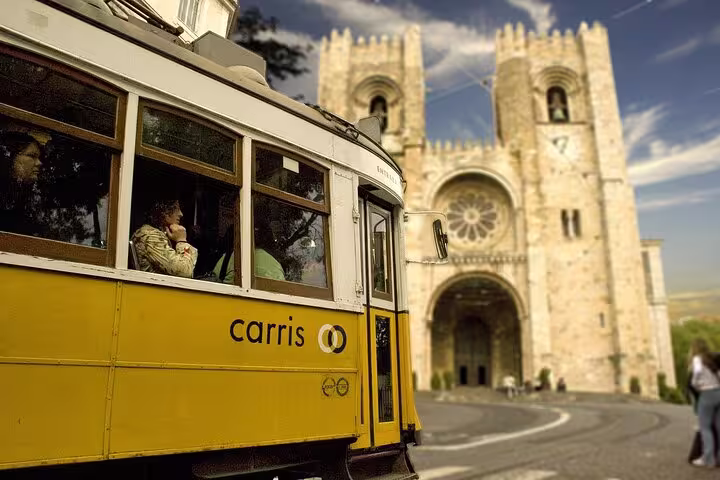 Iconic yellow tram passing Lisbon Cathedral during a private walking tour, showcasing historic Lisbon charm.