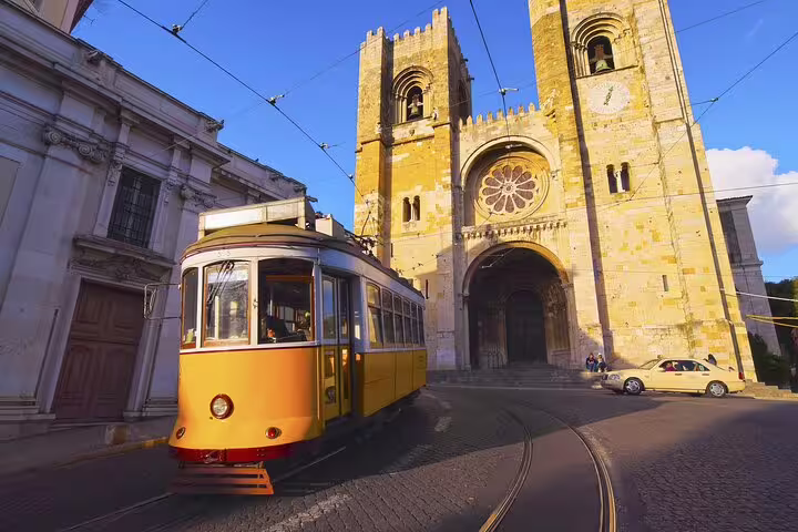 Yellow tram passing Lisbon Cathedral on a sunny day during a private walking tour showcasing the city's highlights and secrets.