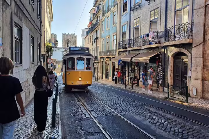 Vintage yellow tram navigating the charming cobblestone streets of Lisbon's Old Town, capturing local architecture and vibrant life.