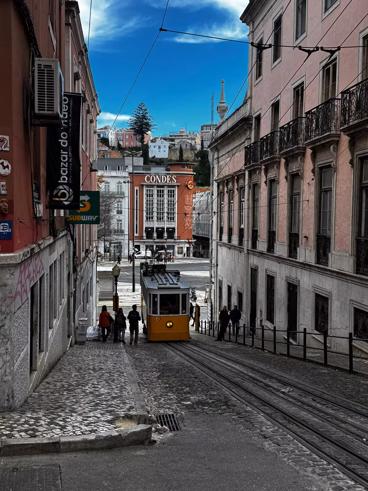 Yellow Lisbon tram on a steep cobbled street near Restauradores, landmark for audio guided City Quest scavenger hunt