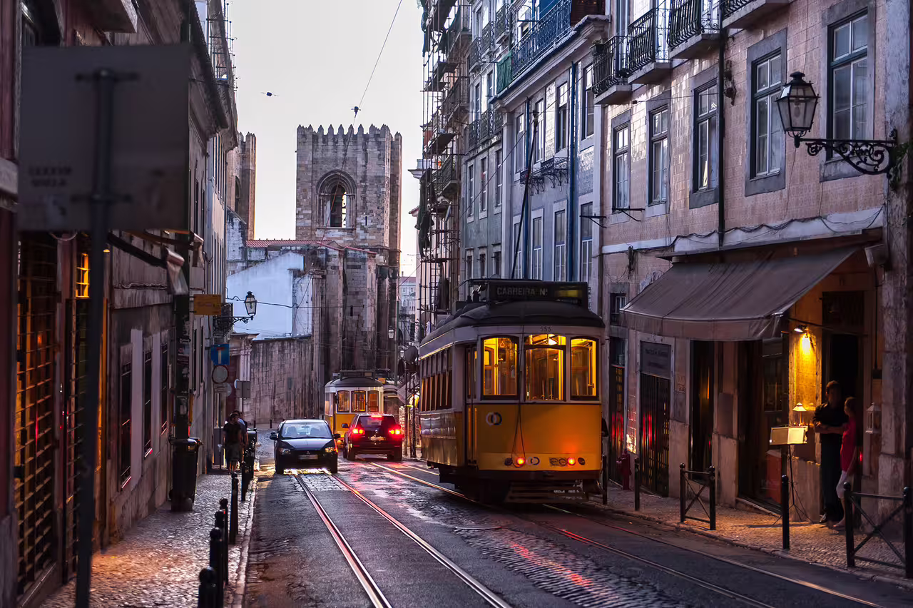 Lisbon's iconic yellow tram navigating historic streets at dusk, perfect for scenic Lisbon to Seville transfer tours.