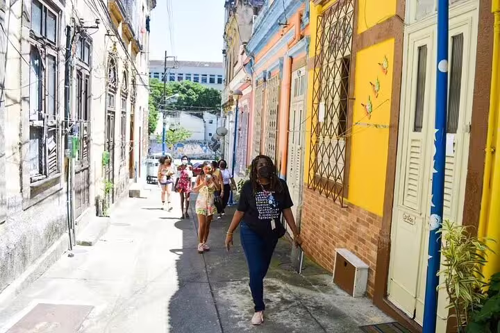 Tour group strolls through colorful alleys of Rio's Little Africa, experiencing rich Afro-Brazilian cultural heritage.