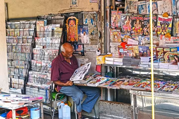 Local vendor reading newspaper at a colorful Little India street stall during Singapore 8-hour private tour