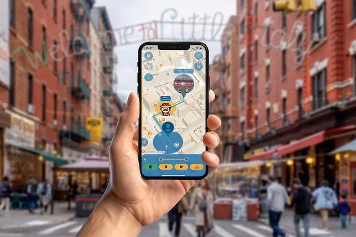 Explorer uses interactive walking tour app in Little Italy NYC with colorful street and Welcome sign backdrop