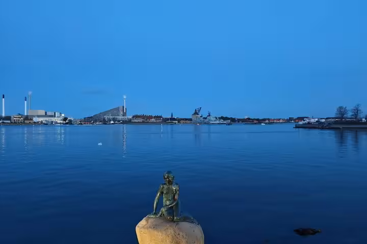 The Little Mermaid bronze statue on a rock in Copenhagen harbour at dusk