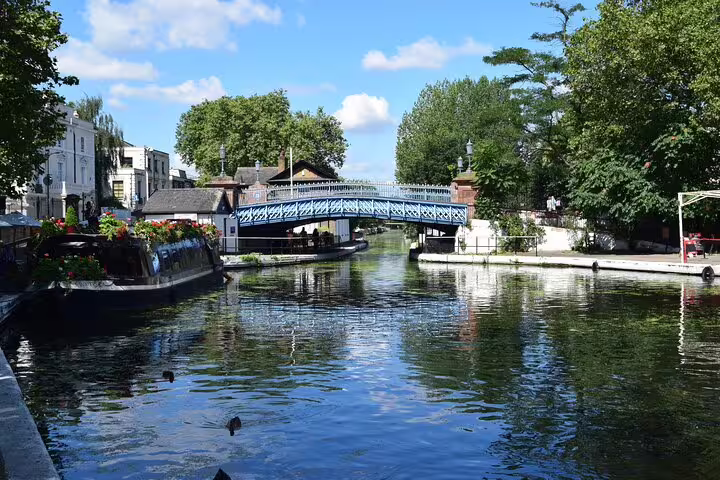 Little Venice London canal with narrowboats and ornate blue iron bridge surrounded by green trees