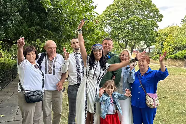 Group of people in traditional embroidered outfits celebrating outdoors in a London park