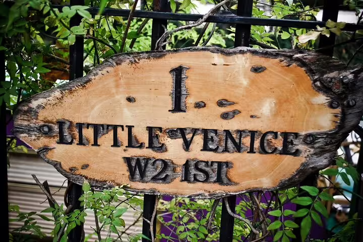 Rustic wooden sign reading 1 Little Venice W2 1ST mounted on black iron gate surrounded by green foliage