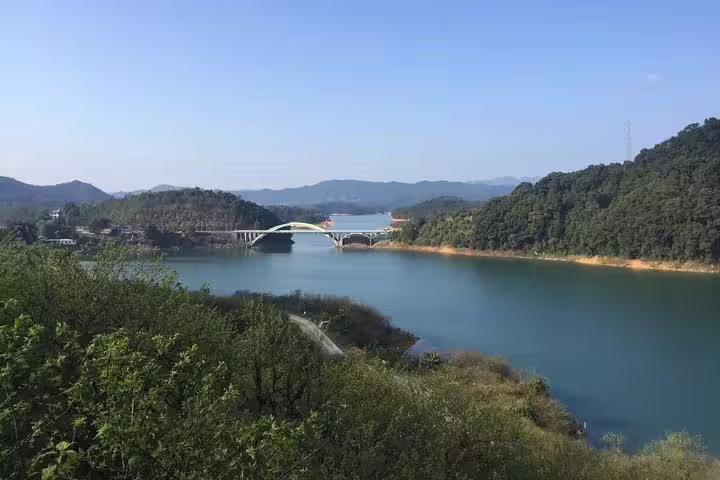 Scenic view of a bridge over a tranquil river surrounded by lush greenery at Liuxihe National Forest Park near Guangzhou.