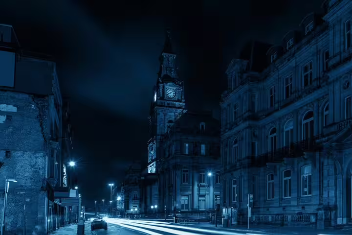 Liverpool city street at night with illuminated clock tower and blue-toned atmospheric lighting