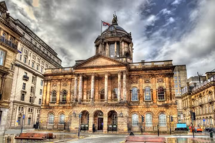Liverpool Town Hall neoclassical facade with dome and Union Jack flag under dramatic cloudy sky