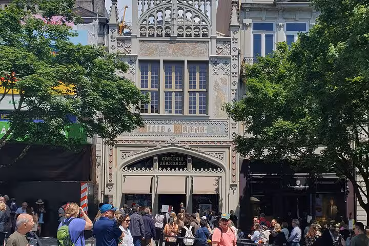 Crowd gathers outside Livraria Lello, a renowned historic bookstore in Porto, famous for its ornate facade.