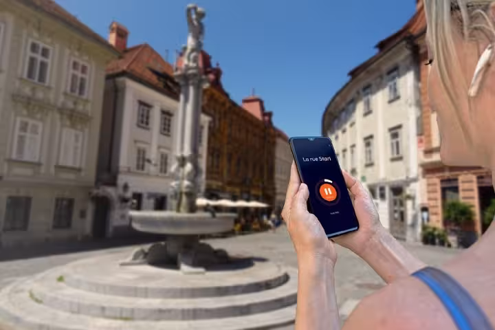 Tourist using audio guide app on smartphone in Ljubljana old town square with fountain