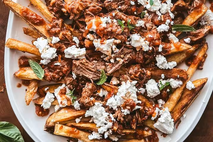 Loaded fries topped with shredded beef, cheese, and herbs, a savory treat on Medellín's street food tour in Laureles.