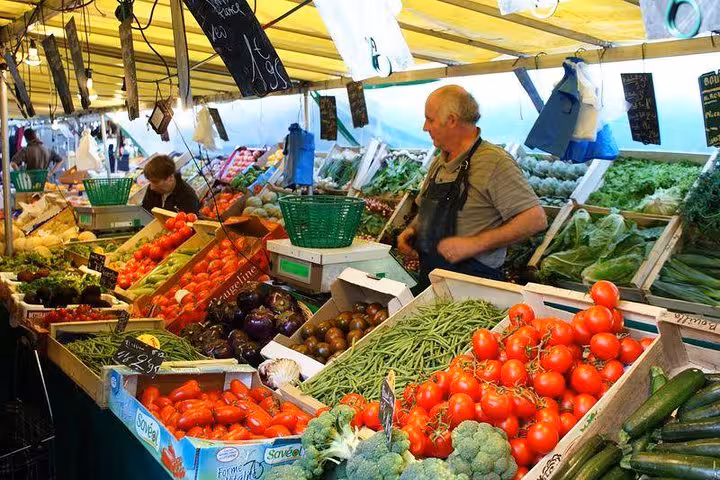 Vibrant vegetable stalls with fresh produce at a bustling local market near the Marais, ideal for a walking food tour.