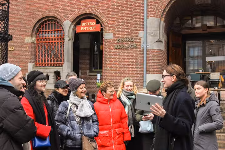 Local guide briefing a small group outside a brick bistro, private city walking experience with a local in Amsterdam