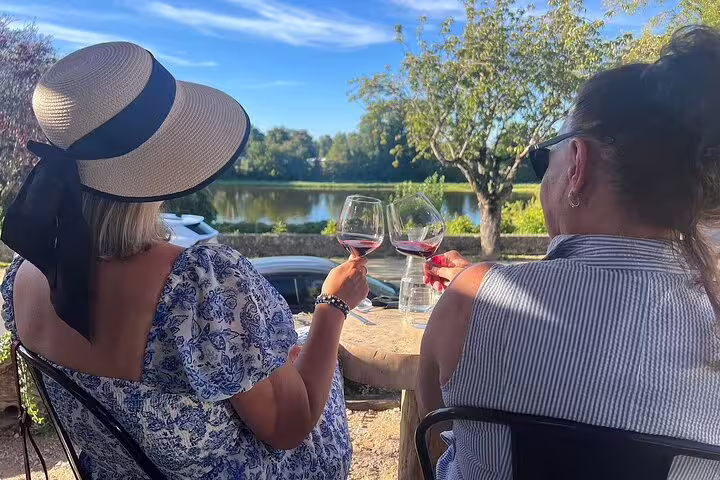 Guests sip Loire Valley red wine by the river on a tasting tour with château visits and lunch included