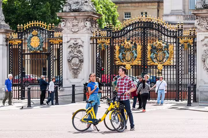 Cyclists enjoy a private bike tour in front of Buckingham Palace's gates, highlighting London's iconic landmarks with lunch included.