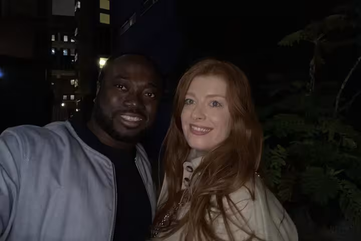 Two smiling people posing together at night near London Bridge area