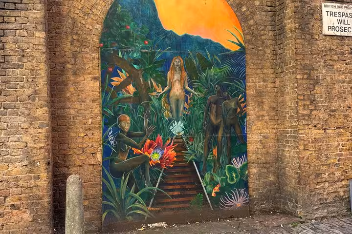 Vibrant street mural of jungle scene with figures painted on brick arch wall near London Bridge