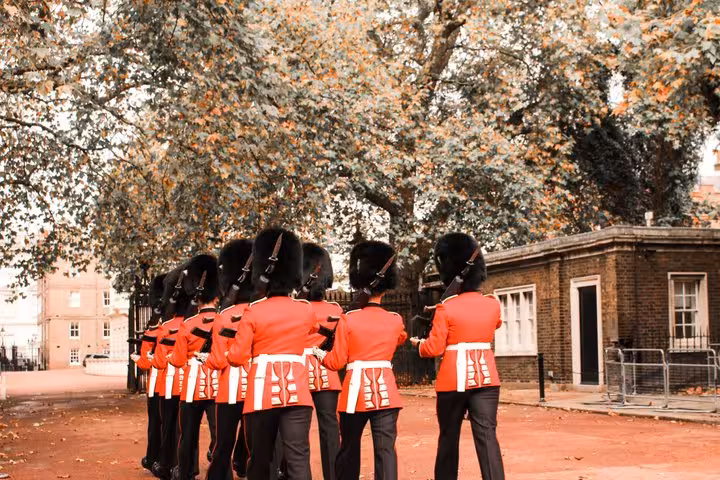 Royal Guards in red tunics and bearskin hats marching during London Changing of the Guard walking tour