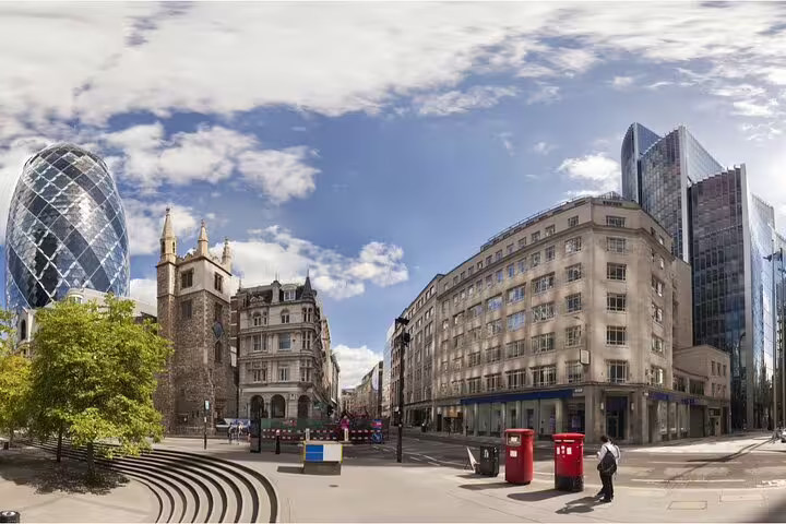 Panoramic view of London city streets with The Gherkin skyscraper, historic church, and red post boxes
