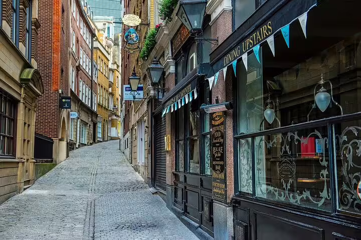 Narrow cobblestone alley with historic brick buildings and a pub in London