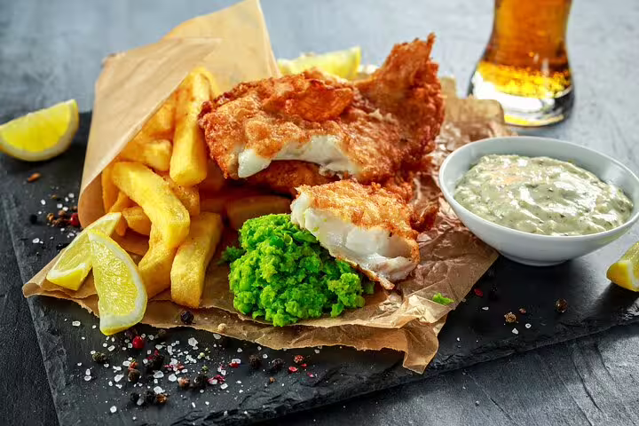 Traditional British fish and chips served with mushy peas and tartar sauce, featured on a London food and drinks private tour.