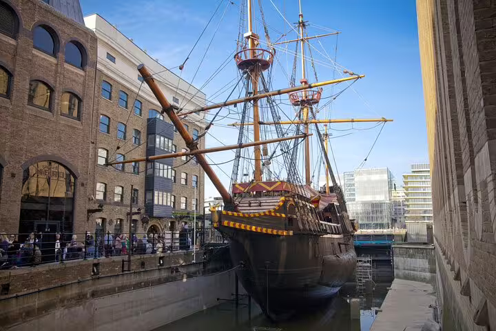 Historic ship docked in London surrounded by modern buildings, showcasing city's blend of maritime heritage and urban architecture.