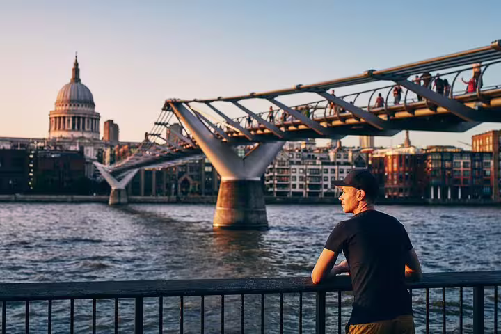 A man enjoys views of the Millennium Bridge and St. Paul's Cathedral in London, perfect for a private skip-the-line Tower of London tour.