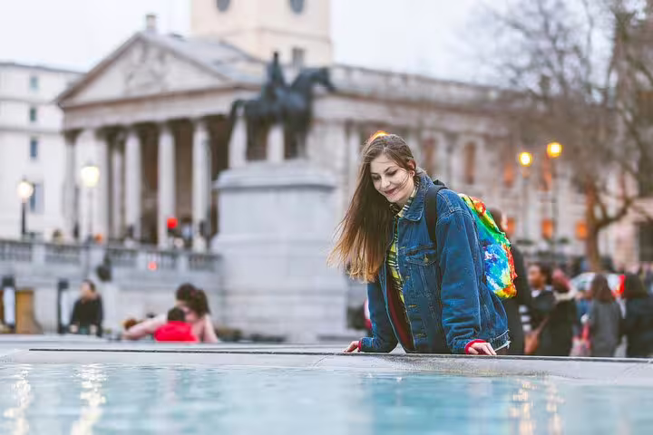 Young woman enjoying the vibrant atmosphere of Trafalgar Square on a London private tour, highlighting Notting Hill and markets.