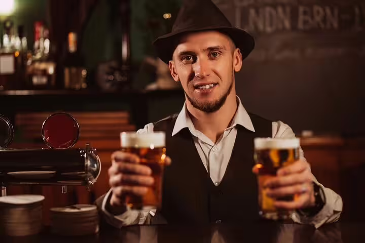 Friendly bartender in a traditional London pub offering two pints of beer during a British Taverns & Pubs private tour.